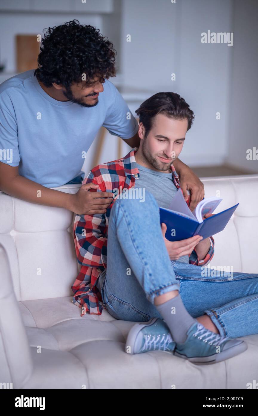 Maschio sorridente che abbraccia un giovane con un libro di testo Foto Stock