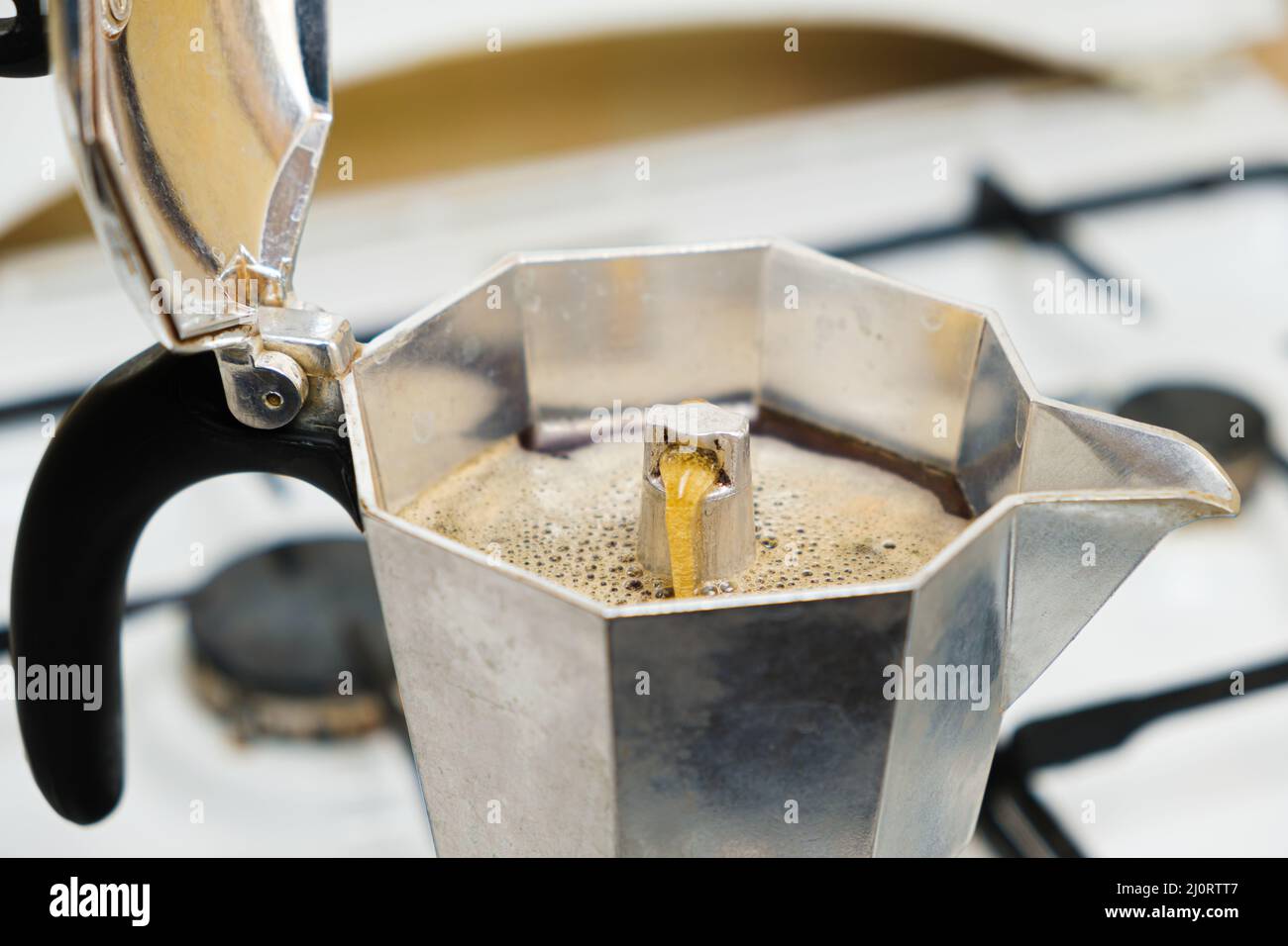 Caffè caldo appena fatto in una macchina per il caffè geyser in piedi su una stufa a gas Foto Stock