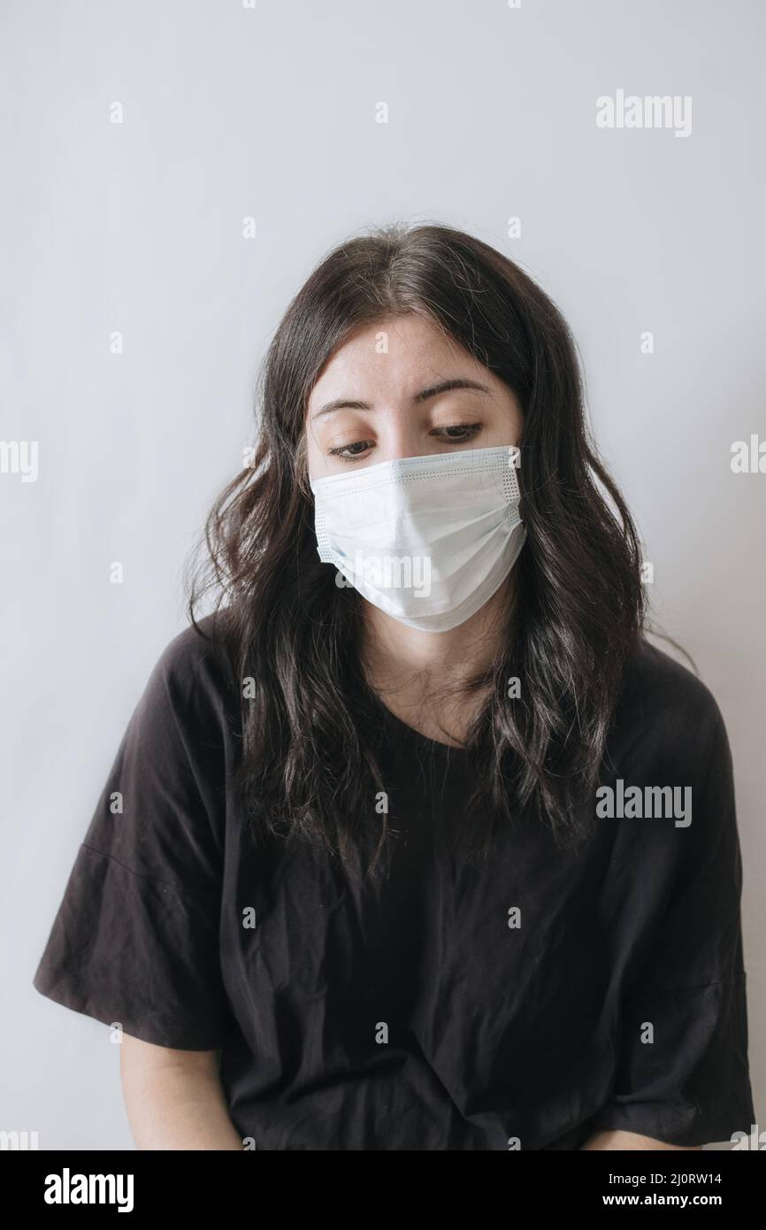 Concetto di Covid, assistenza sanitaria e pandemia. Donna asiatica in t-shirt nera e maschera medica e guardando triste e deluso alla macchina fotografica. Foto Stock