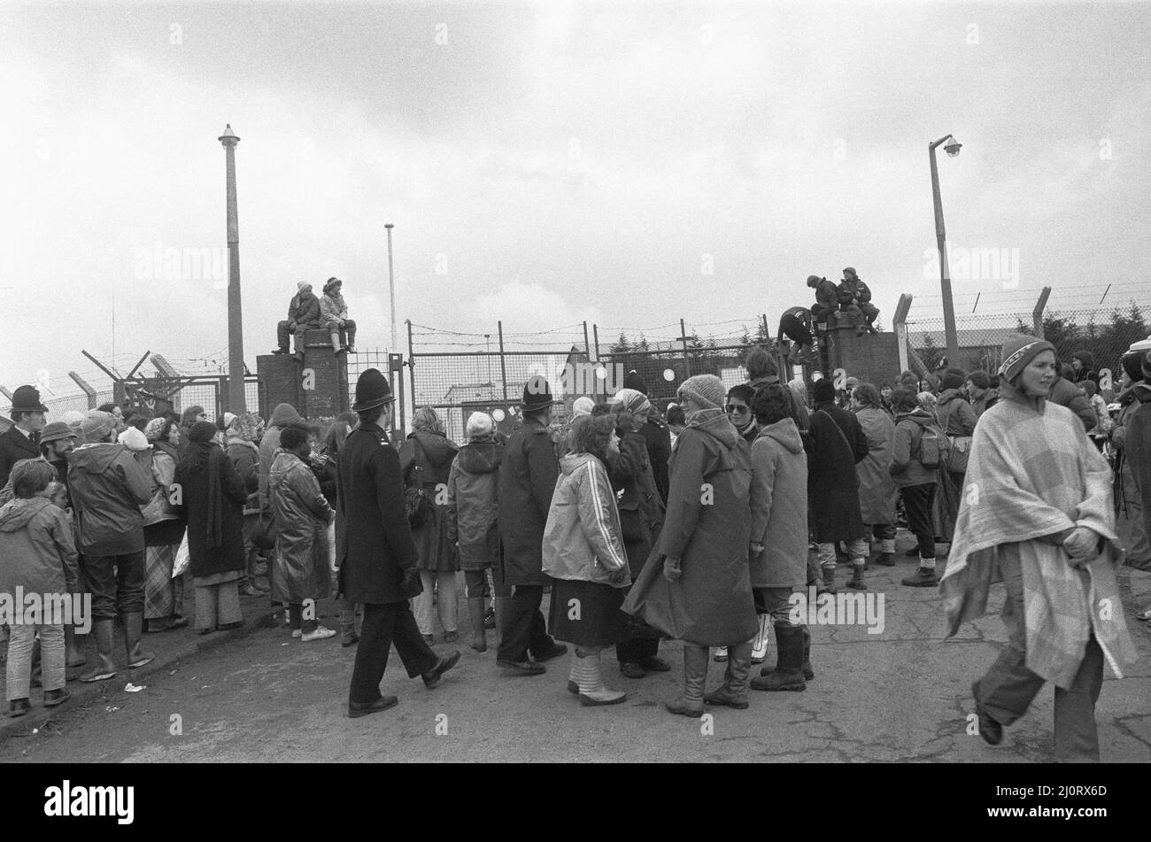 70.000 manifestanti convergono sul campo della Pace delle Donne a Greenham Common e sullo stabilimento delle armi nucleari ad Aldermarston per creare una catena umana di 14 miglia tra le due basi in protesta contro la decisione di disporre i missili da crociera americani a Greenham Common e la proliferazione delle armi nucleari. La nostra immagine mostra: Le donne dal campo di pace che blocca la porta gialla in RAF Greenham Common mentre la polizia tenta di sgombrare la strada 1st aprile 1983 Foto Stock