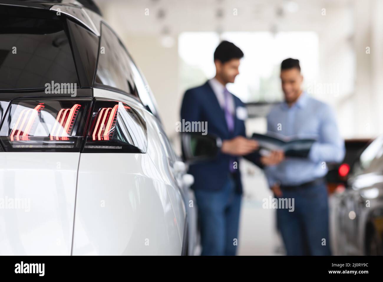 Responsabile vendite irriconoscibile che assiste il cliente maschile presso la concessionaria auto Foto Stock