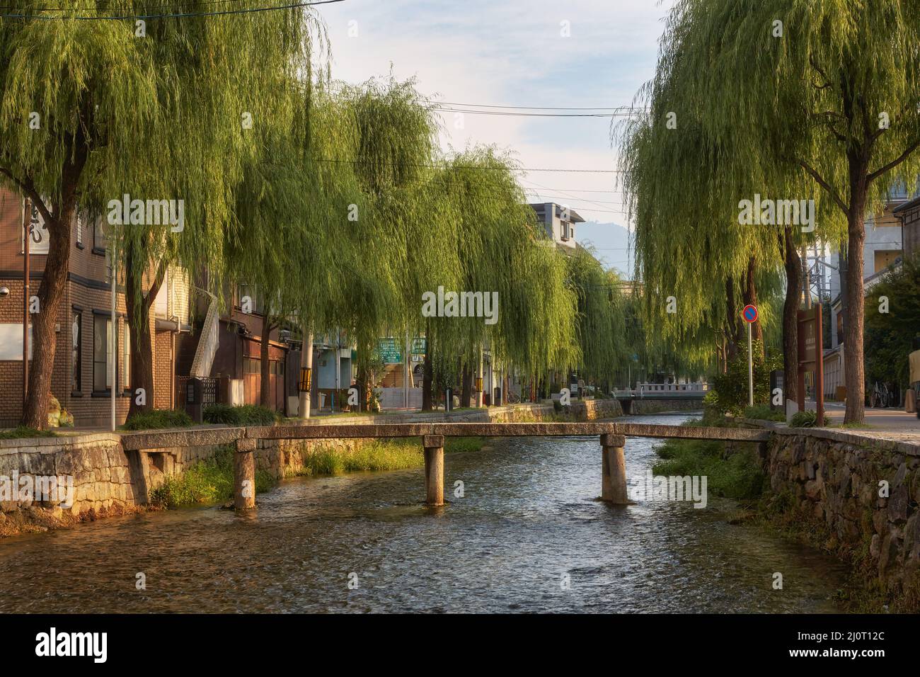 La vista del ponte di pietra sul canale di Shirakawa fiancheggiato da alberi di salice. Kyoto, Giappone Foto Stock