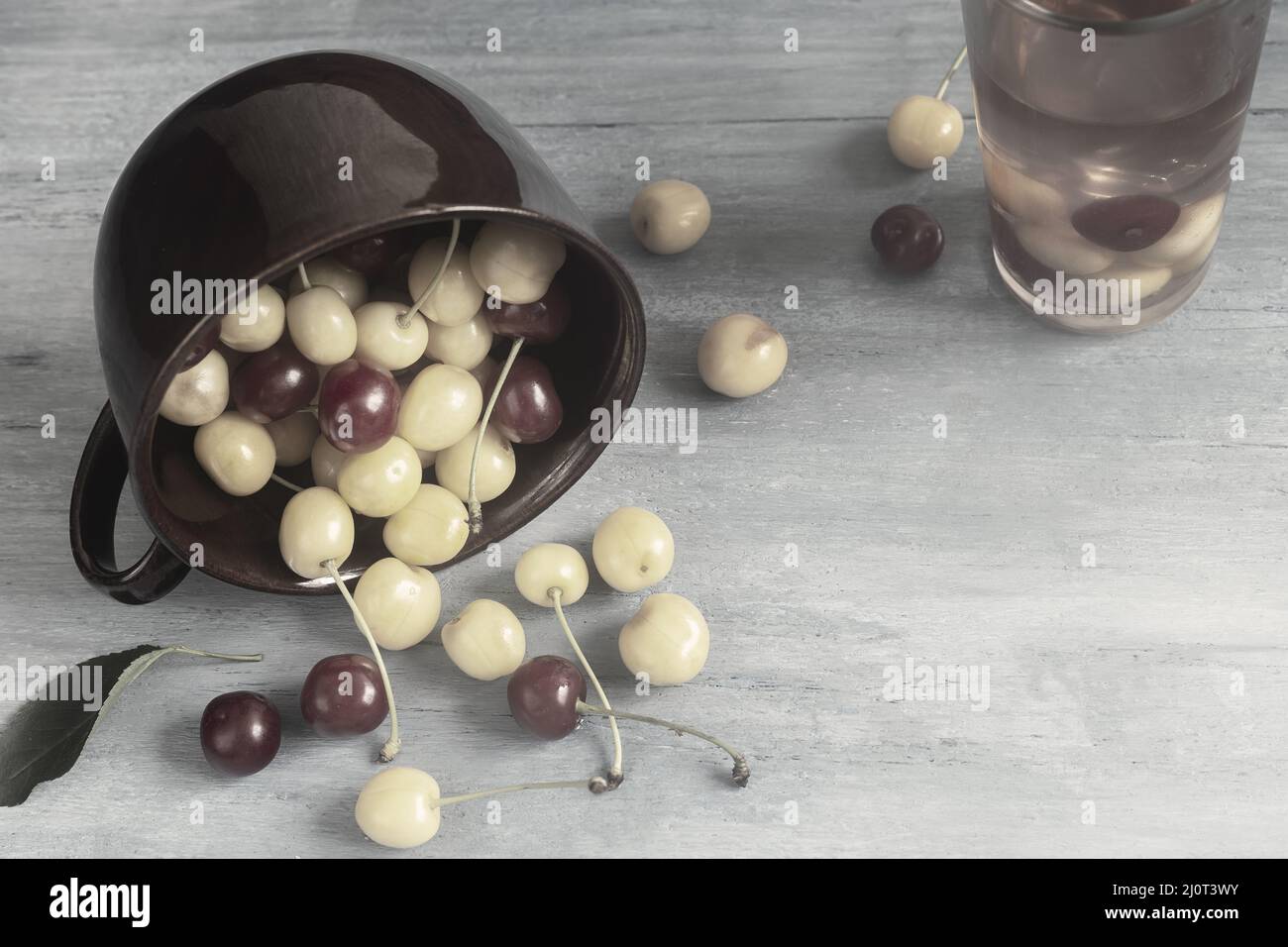 Ciliegie gialle e rosse in una tazza di ceramica Foto Stock