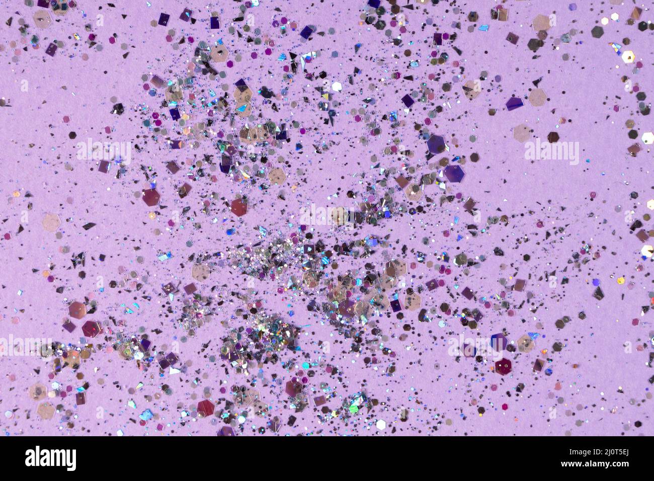 Paillettes olografiche argentate su sfondo viola pastello. Foto di alta qualità Foto Stock