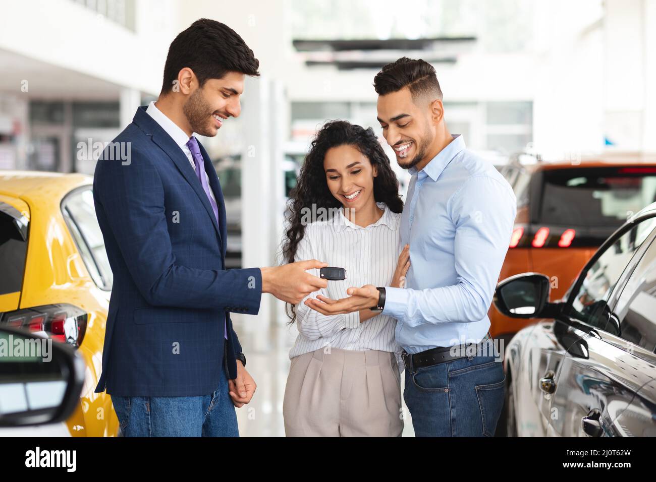 Sorridente responsabile delle vendite che dà la chiave della famiglia medio-orientale da auto Foto Stock
