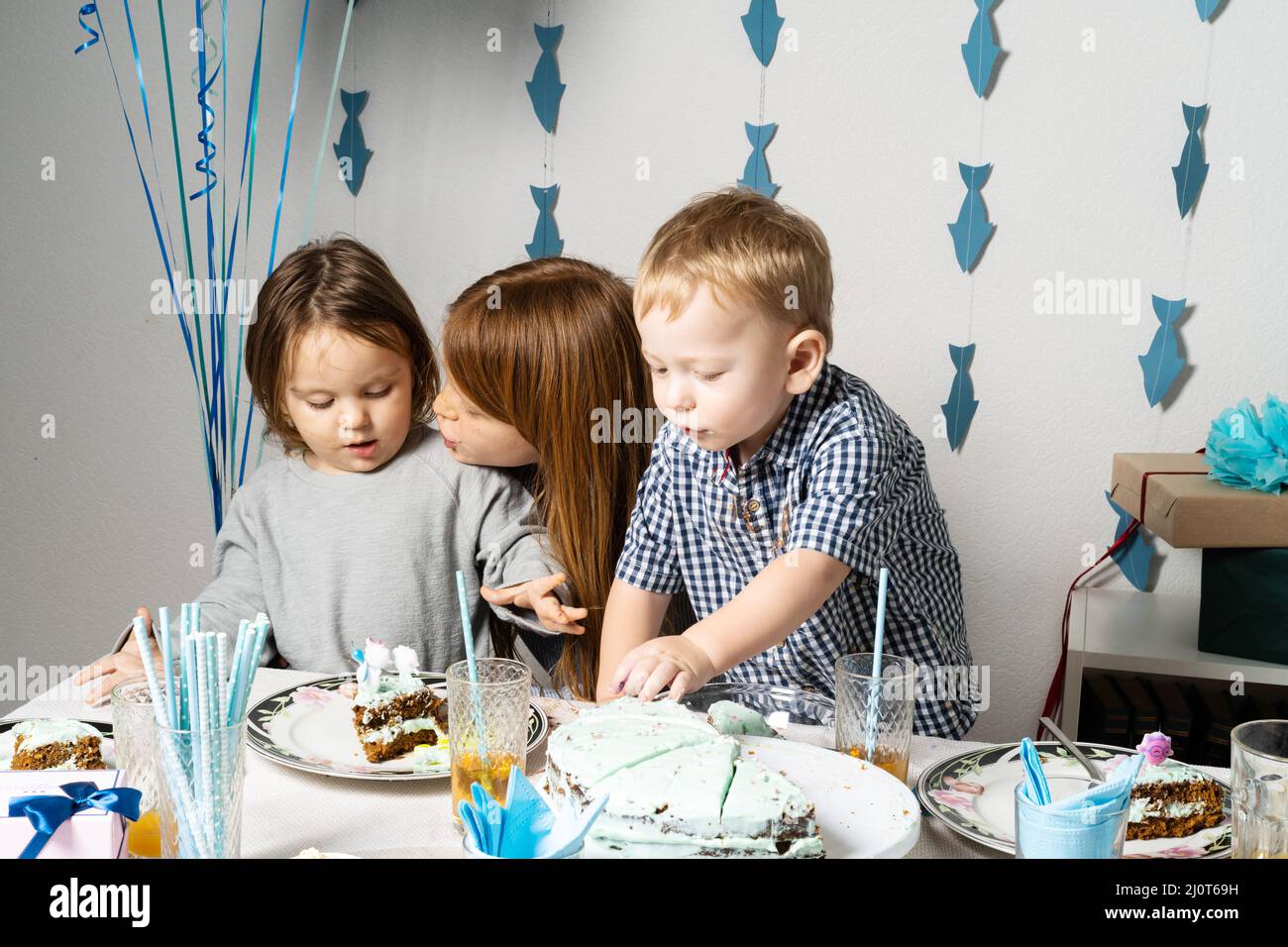 Fratelli. Compleanno del ragazzo al tavolo. I ragazzi al tavolo tagliano una torta di compleanno. Foto Stock