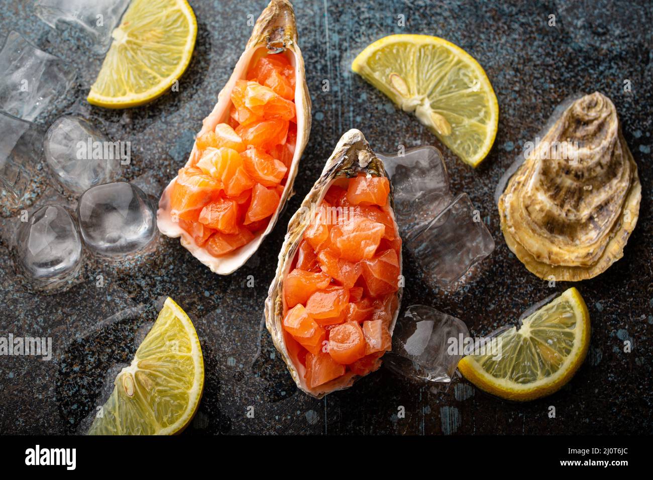 Tartare di salmone crudo tritato servito in conchiglie di ostriche vista dall'alto su sfondo di pietra Foto Stock