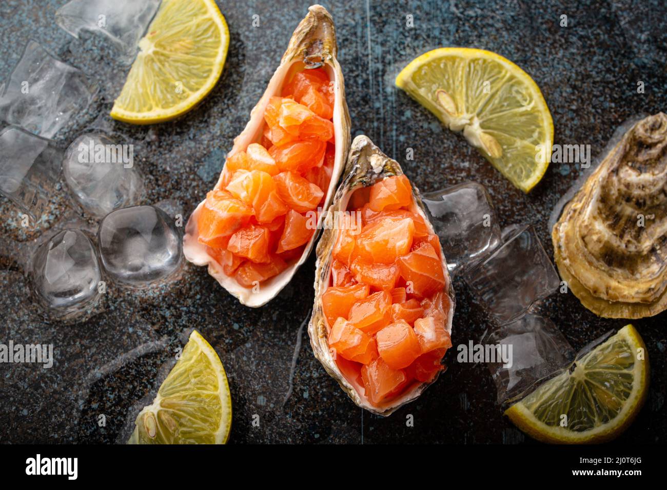 Tartare di salmone crudo tritato servito in conchiglie di ostriche vista dall'alto su sfondo di pietra Foto Stock