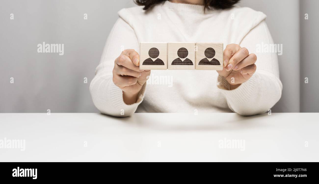 La donna siede ad un tavolo e tiene i cubetti di legno. Il concetto di reclutare un team nel business, trovare dipendenti di talento. Leader i Foto Stock