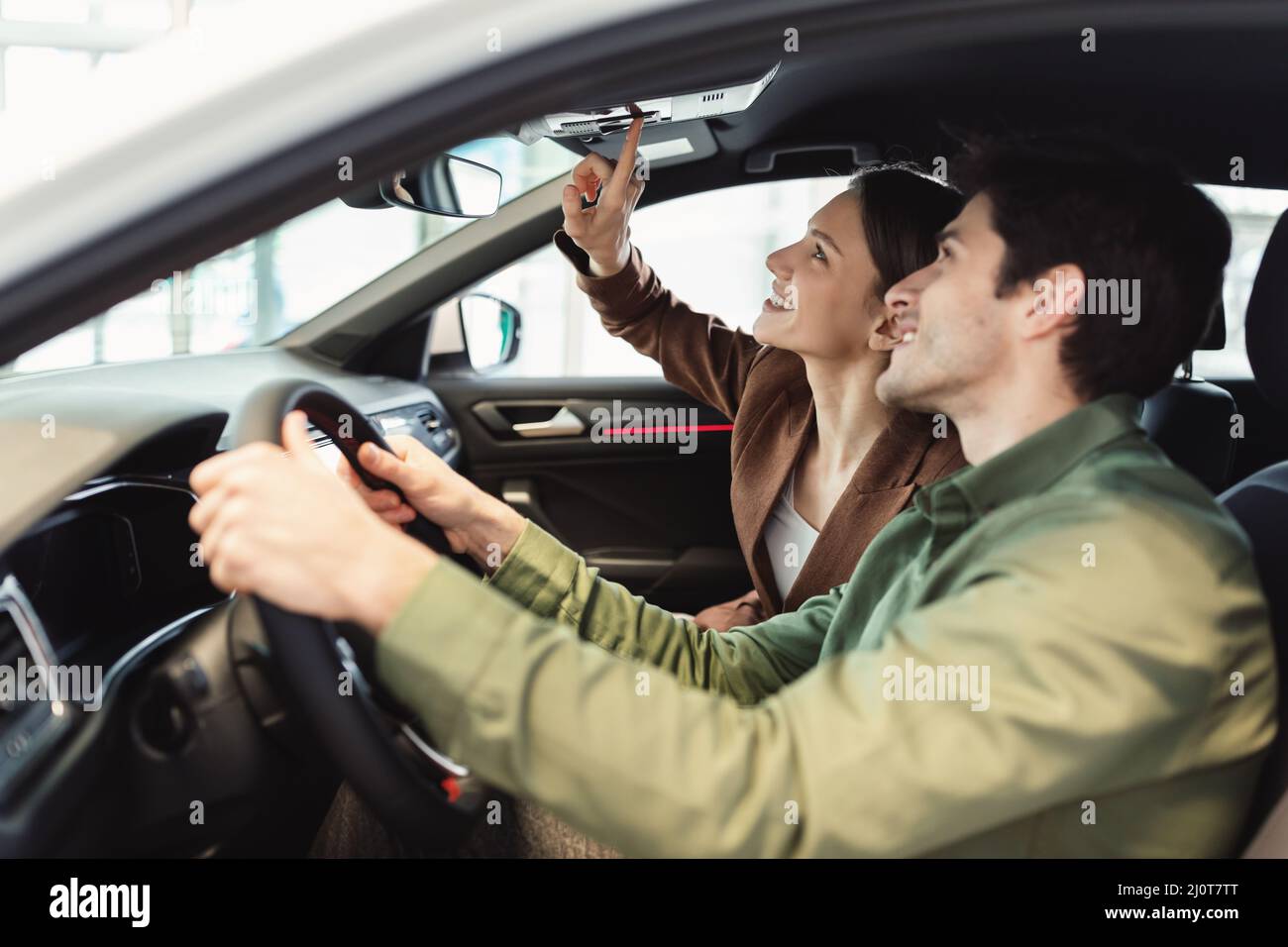 Happy millennial coppia prova guida nuova auto presso la concessionaria automobilistica Foto Stock