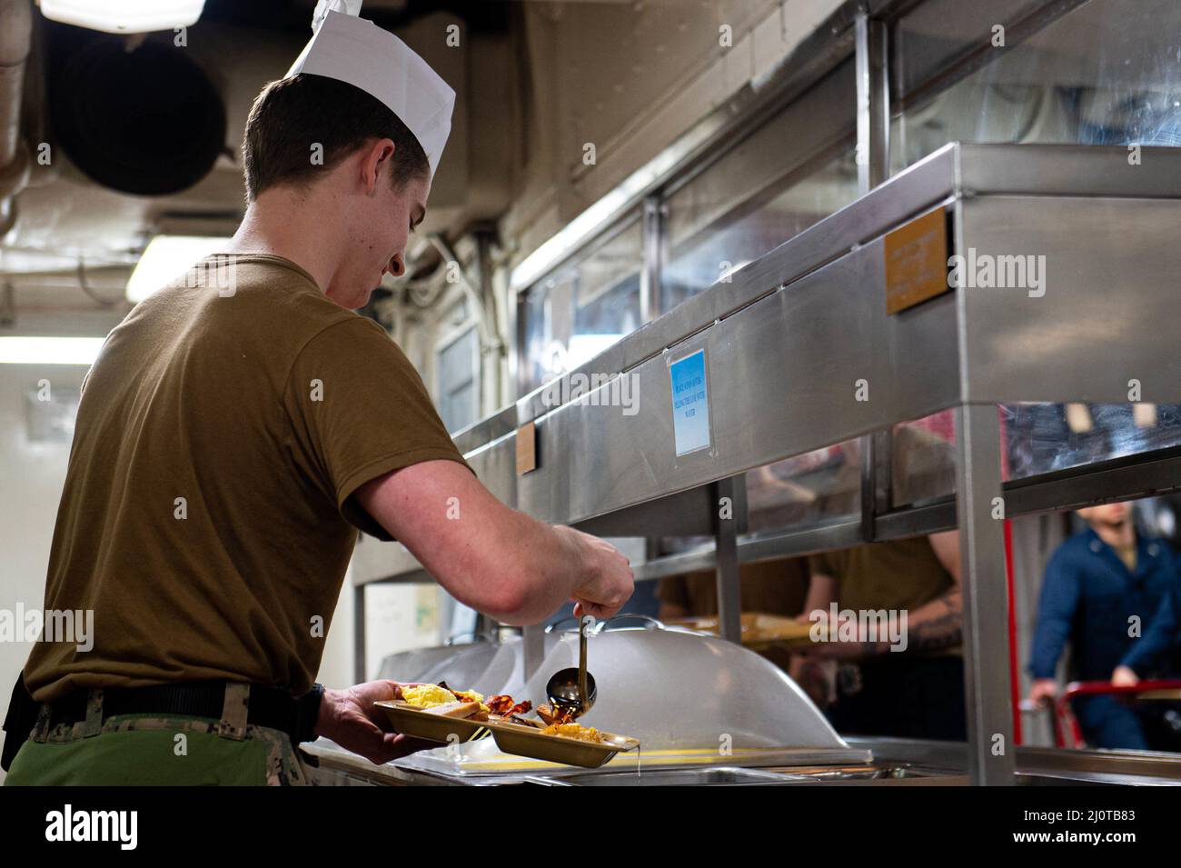 220122-N-TD381-1005 MAR DELLE FILIPPINE (GEN. 22, 2022) Naval Aircrewman (elicottero) 3rd Class Matthew Wood, nativo di Long Beach, California, serve la colazione ai marinai nella cucina in avanti del vettore aereo di classe Nimitz USS Carl Vinson (CVN 70), 22 gennaio 2022. Operando come parte della U.S. Pacific Fleet, la USS Carl Vinson sta conducendo corsi di formazione per preservare e proteggere una regione indopacifica libera e aperta. (STATI UNITI Foto della Marina di SMass Communication Specialist Seaman Apprentice Isaiah B. Goessl) Foto Stock