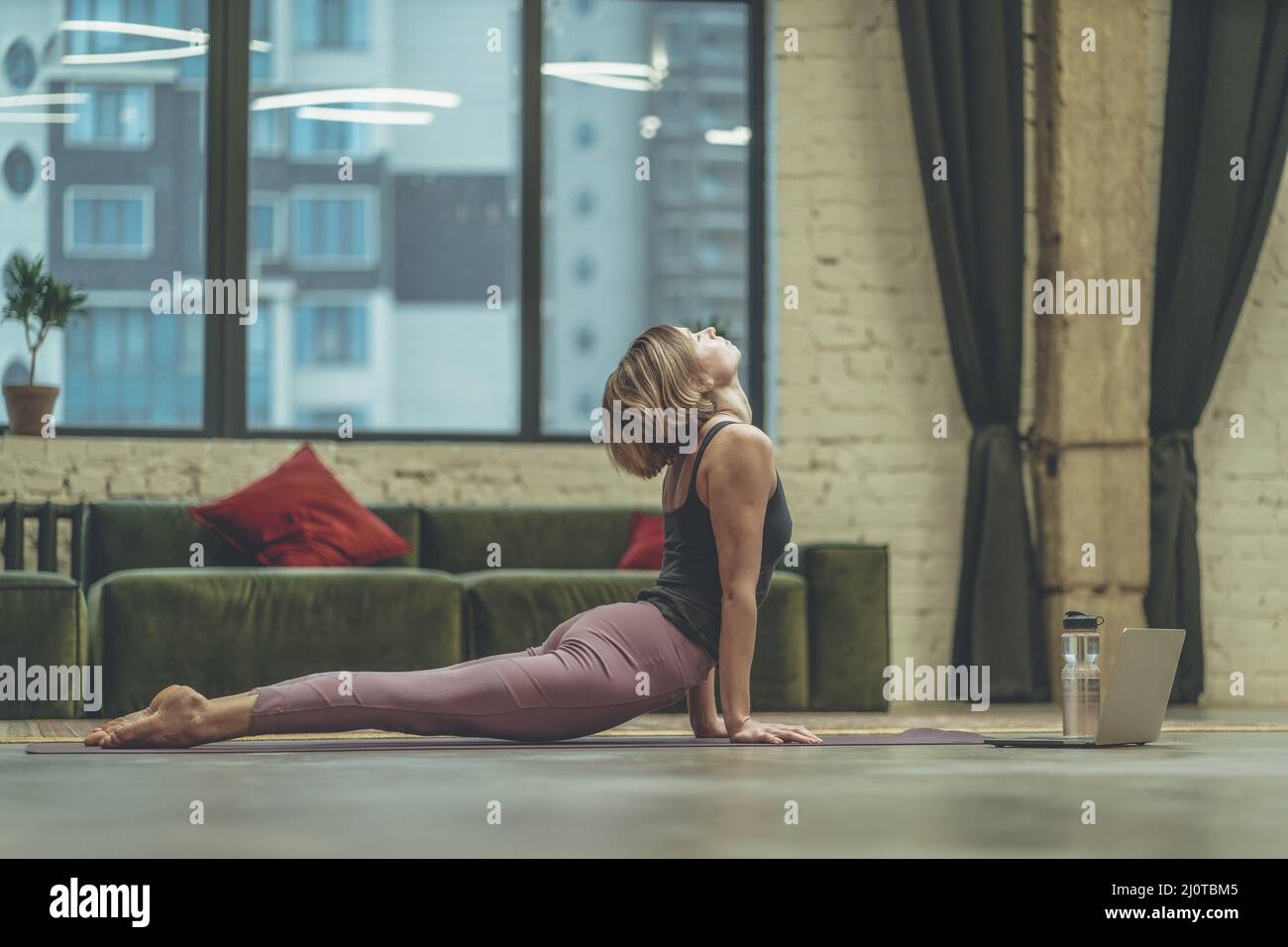 Giovane donna che fa Yoga Asana Cobra sul tappetino Yoga sul pavimento a casa. Allenamento domestico, rinforzando i muscoli posteriori. Primo piano Foto Stock