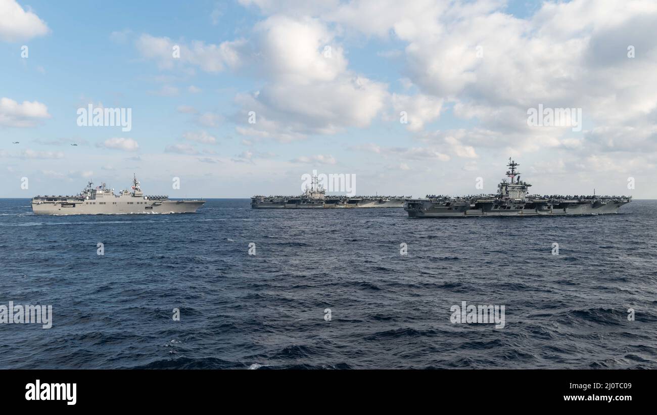 MAR DELLE FILIPPINE (Gen. 22, 2022) nave d'assalto anfibio di classe americana USS America (LHA 6), posteriore sinistra, forza di autodifesa marittima giapponese (JMSDF) caccia all'elicottero di classe Hyūga JS Hyūga (DDDH 181), anteriore sinistra, vettori aerei di classe Nimitz USS Carl Vinson (CVN 70), centrale, e USS Abraham Lincoln (CVN 72) transitano sul Mare delle Filippine, 22 gennaio 2022. Operando come parte della flotta del Pacifico degli Stati Uniti, le unità assegnate ai gruppi di colpo della portante di Carl Vinson ed Abraham Lincoln, gli Stati Uniti ed i gruppi anfibi pronti dell'Essex, insieme alla forza marittima di auto-difesa del Giappone, stanno conducendo l'addestramento per conservare e proteggere a. Foto Stock