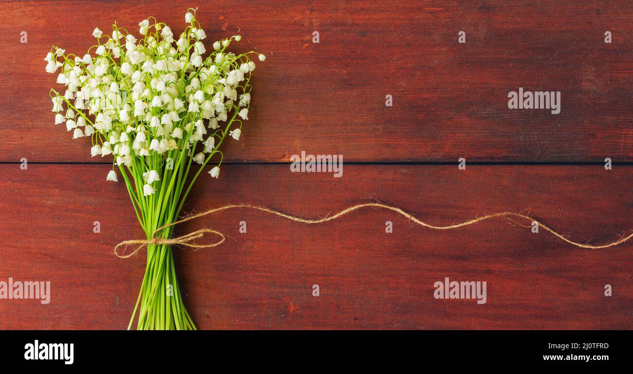 Gigli di fiori bianchi della valle su tavole di legno marrone. Spazio di copia. Spazio libero per il testo Foto Stock