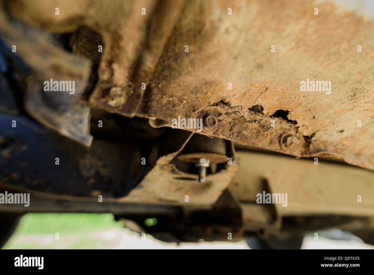 Primo piano interventi di riparazione e saldatura della carrozzeria necessari. Ruggine su una vecchia auto grigia. Foro di ruggine su una vecchia superficie metallica verniciata usurata. Foto Stock