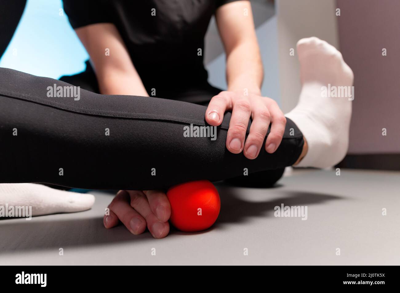 Primo piano giovane massaggiatrice maschile insegna ad un cliente caucasico donna miofasciale auto-massaggio utilizzando una palla da massaggio interno. MYO Foto Stock