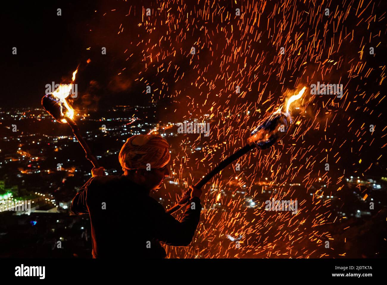 Akre, Iraq. 20th Mar 2022. Un uomo curdo iracheno tiene le torce di fuoco mentre si trova su una montagna durante le celebrazioni del nuovo anno curdo 'Newroz' nella città di Akre. Credit: Ismael Adnan/dpa/Alamy Live News Foto Stock