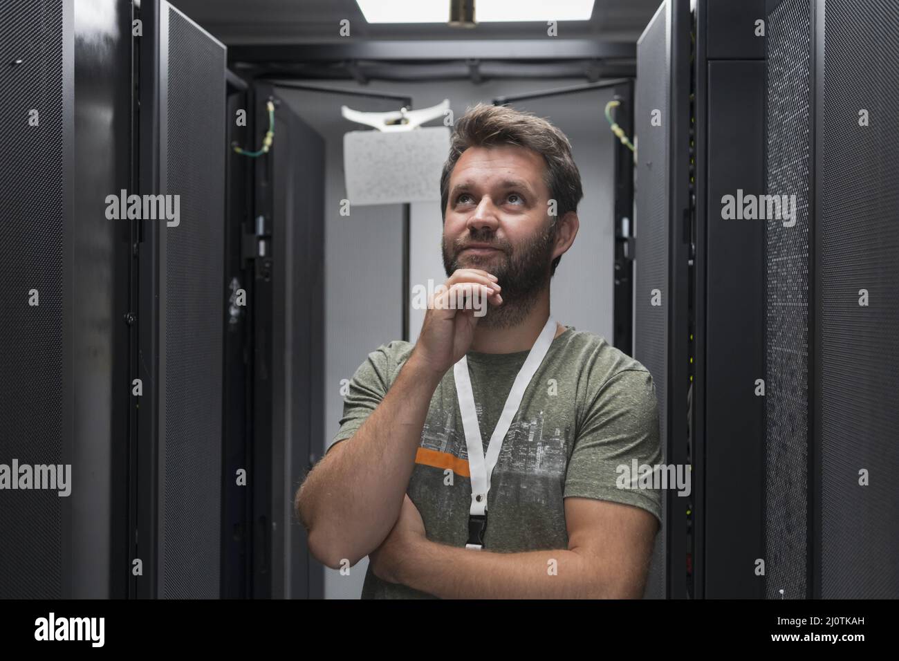 Ritratto di un tecnico maschile o di un amministratore di rete coraggioso come un eroe con le braccia incrociate nella sala server del data center. Foto Stock