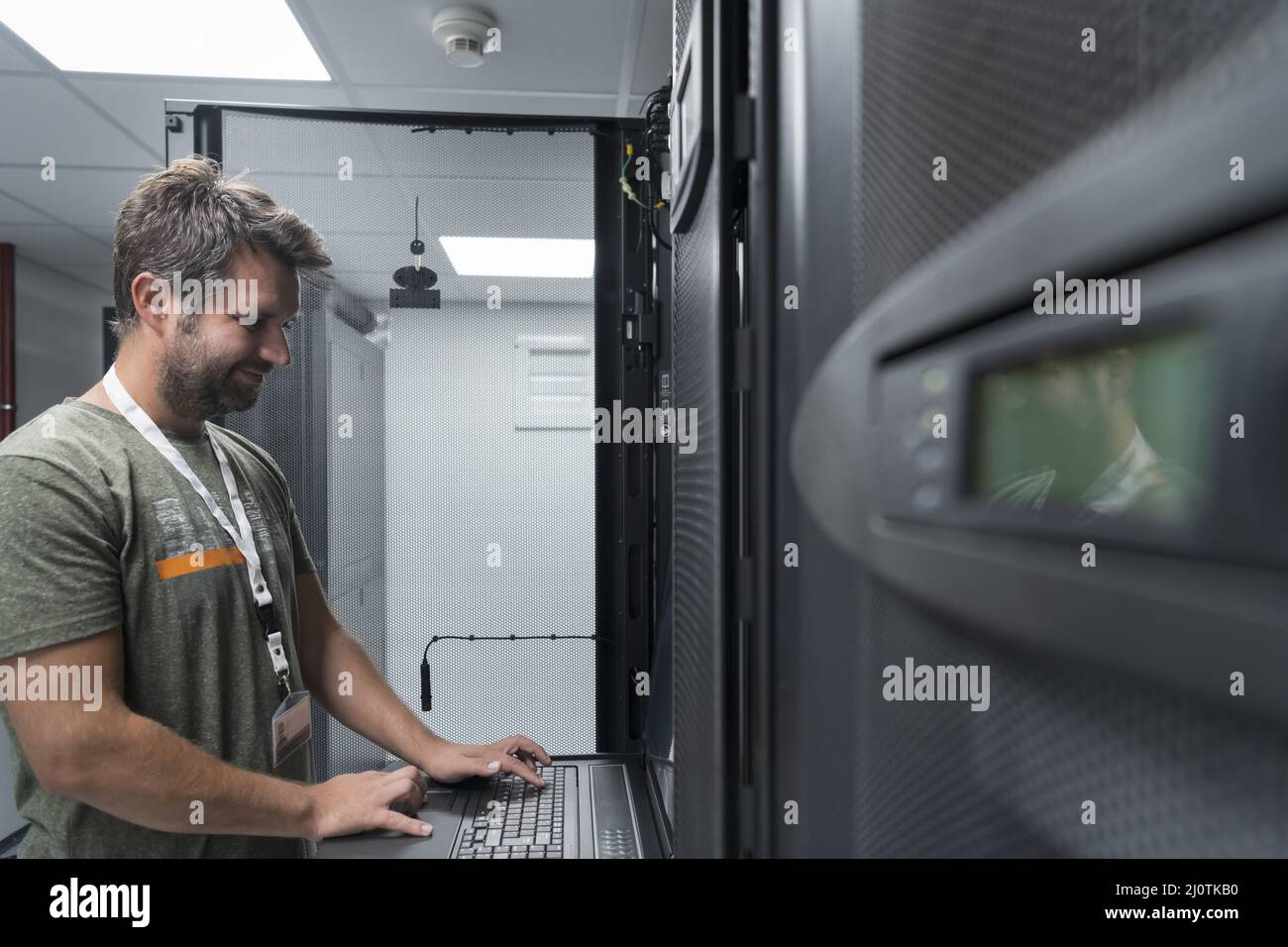 Ingegnere del data center, tastiera su una struttura specializzata Supercomputer Server Room con amministratore di sistema maschio Foto Stock