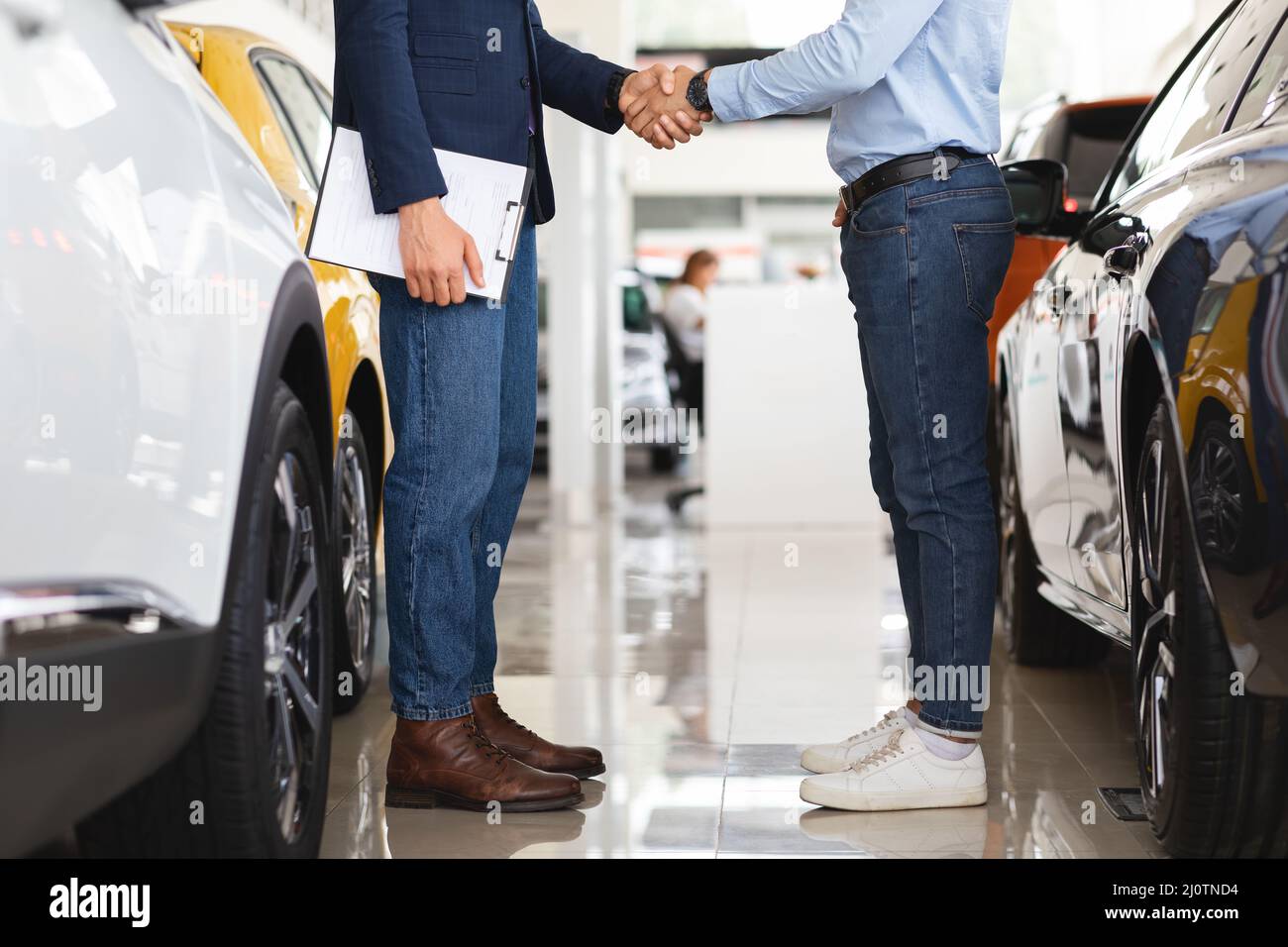 Il responsabile delle vendite agita la mano del cliente, lo showroom auto Foto Stock