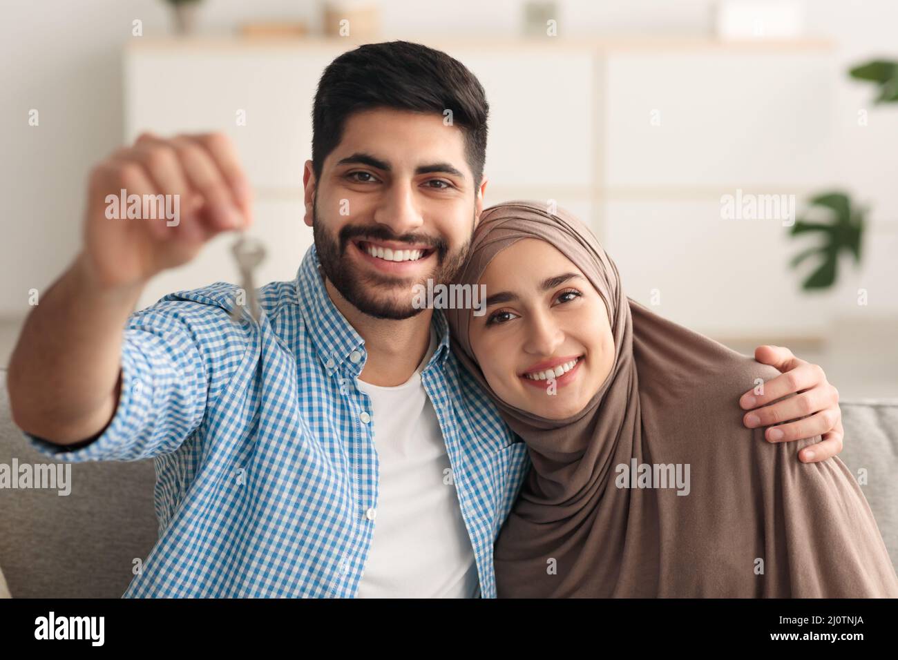 Gioiosa coppia mediorientale che mostra Key sorridente seduto a casa Foto Stock