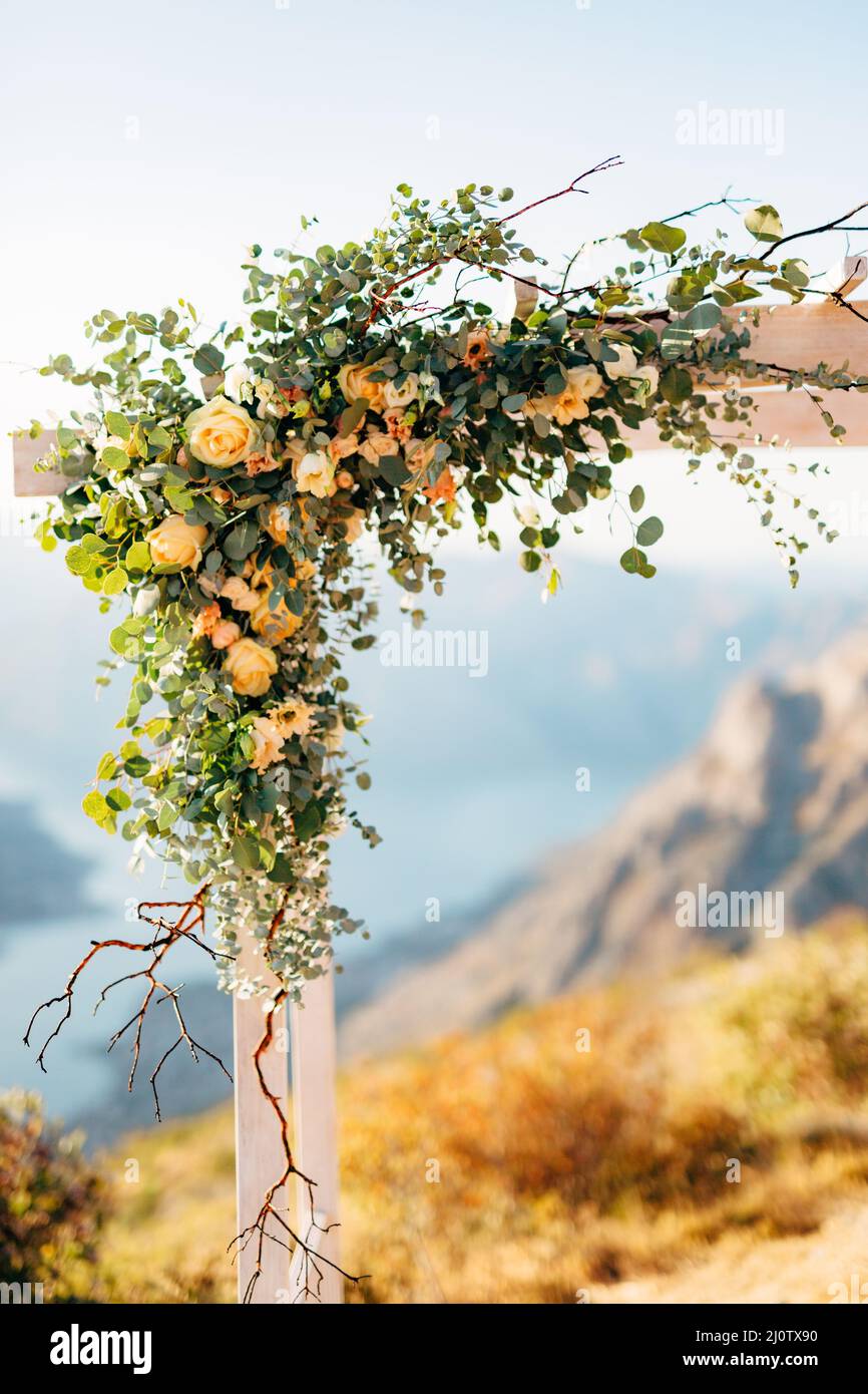 Angolo dell'arco di nozze decorato con rose e rami verdi sullo sfondo delle montagne Foto Stock