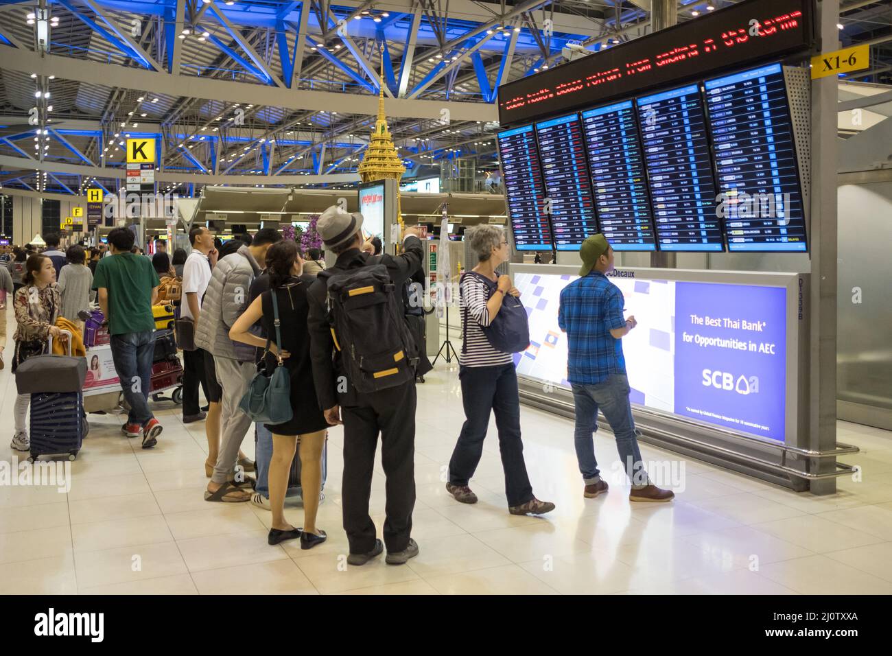 I viaggiatori che controllano le partenze all'Aeroporto Suvarnabhumi di Bangkok. Si tratta di uno degli aeroporti più trafficati del mondo. Foto Stock