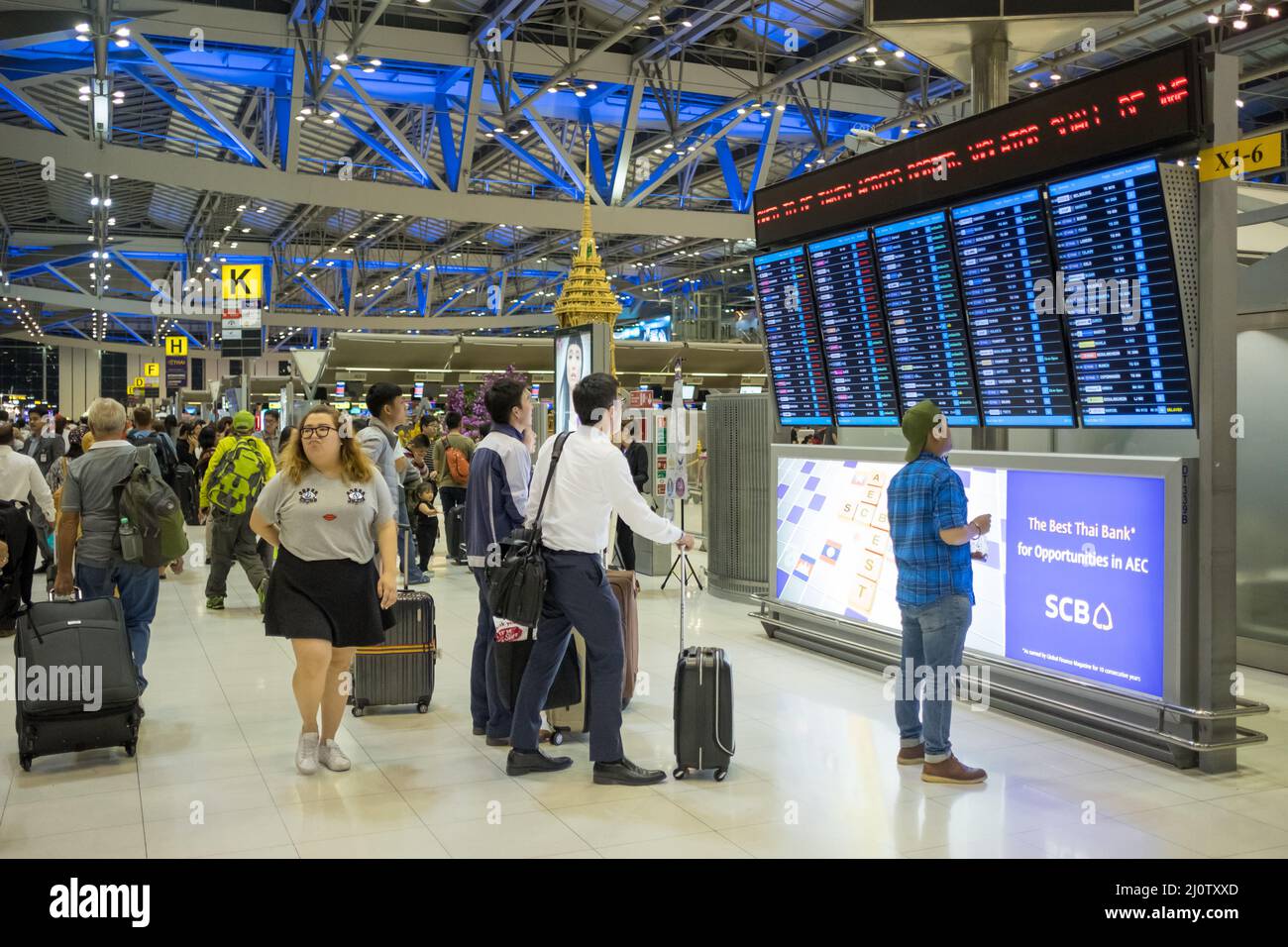 I viaggiatori che controllano le partenze all'Aeroporto Suvarnabhumi di Bangkok. Si tratta di uno degli aeroporti più trafficati del mondo. Foto Stock