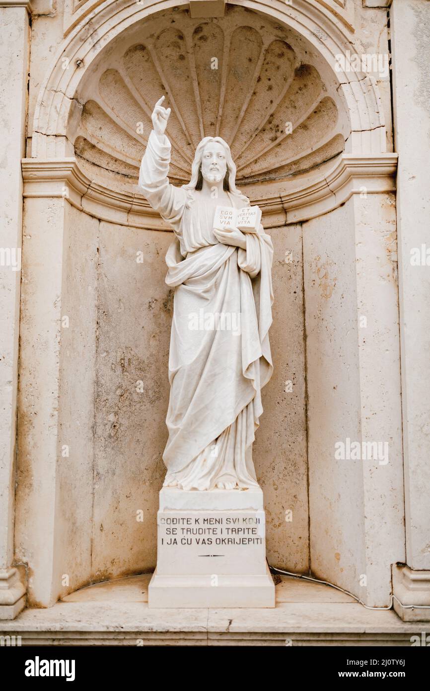 Statua di Gesù Cristo con un libro nelle mani vicino alla Chiesa della Natività della Vergine a Prcanj Foto Stock