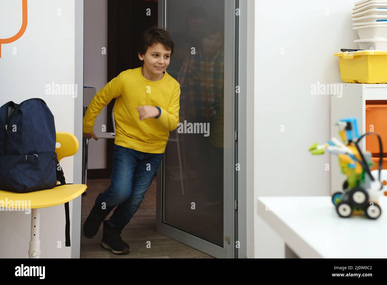 Bambini alunni che corrono nella stanza della scuola sul freno. I bambini felici che si divertono a scuola elementare. Istruzione moderna Foto Stock