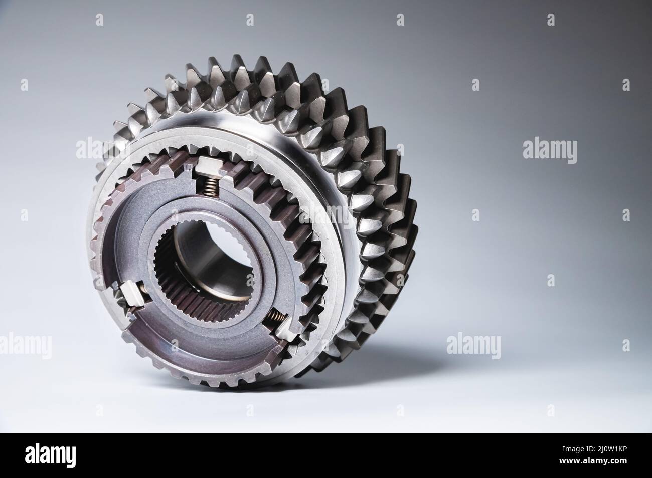 Il nuovo ingranaggio in metallo lucido della scatola interruttori è dotato di uno sfondo grigio a gradiente. Il concetto di nuovi pezzi di ricambio per auto principale Foto Stock