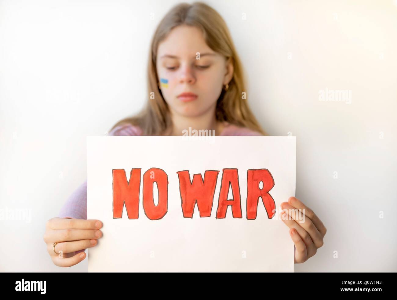 Una ragazza sconvolta con un poster che protestava contro la guerra ha disegnato una bandiera NESSUNA GUERRA su uno sfondo bianco. Bambino contro la guerra, 2022 invasione di russo Foto Stock