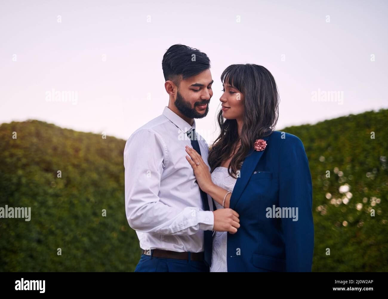 Che cosa è il suo è il suo da ora in poi. Scatto corto di una giovane sposa affettuosa sorridente al suo sposo mentre indossa la sua giacca il giorno del loro matrimonio. Foto Stock