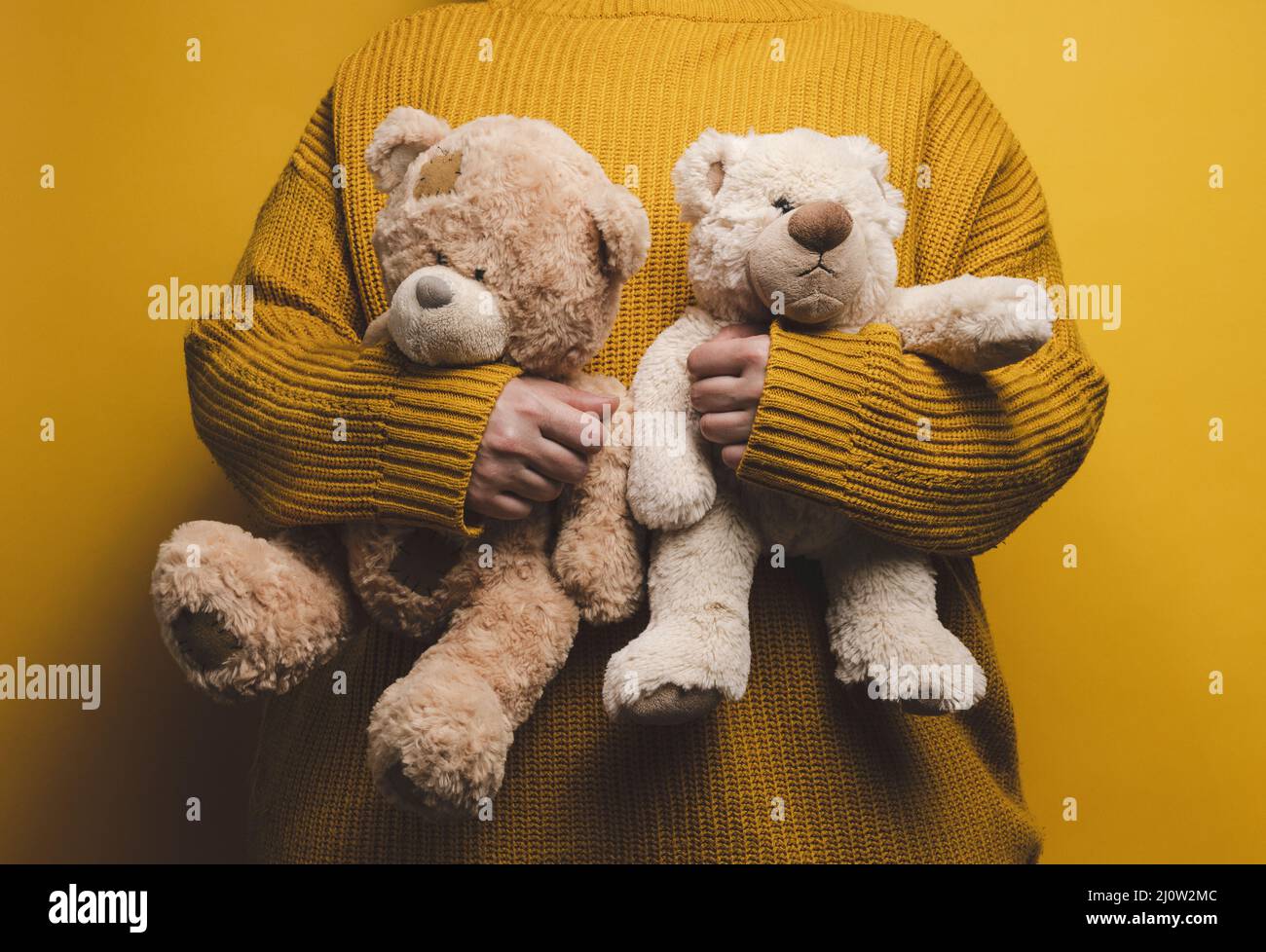 Donna in maglia arancione maglione abbraccia carino orsacchiotto marrone. Il concetto di solitudine e tristezza, depressione Foto Stock