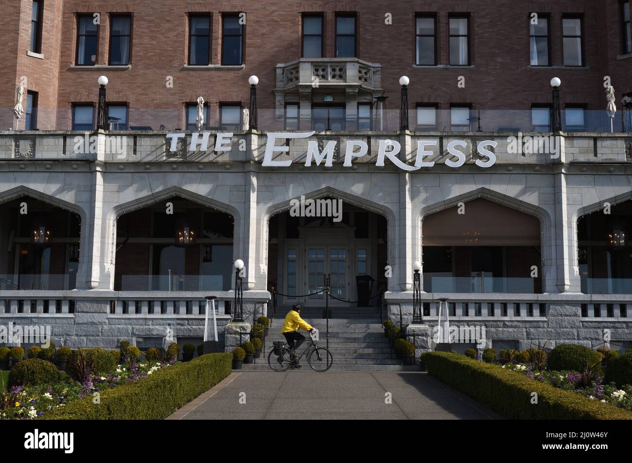 Un ciclista in una giacca gialla passa davanti al Fairmont Empress Hotel a Victoria, British Columbia, Canada sull'isola di Vancouver Foto Stock