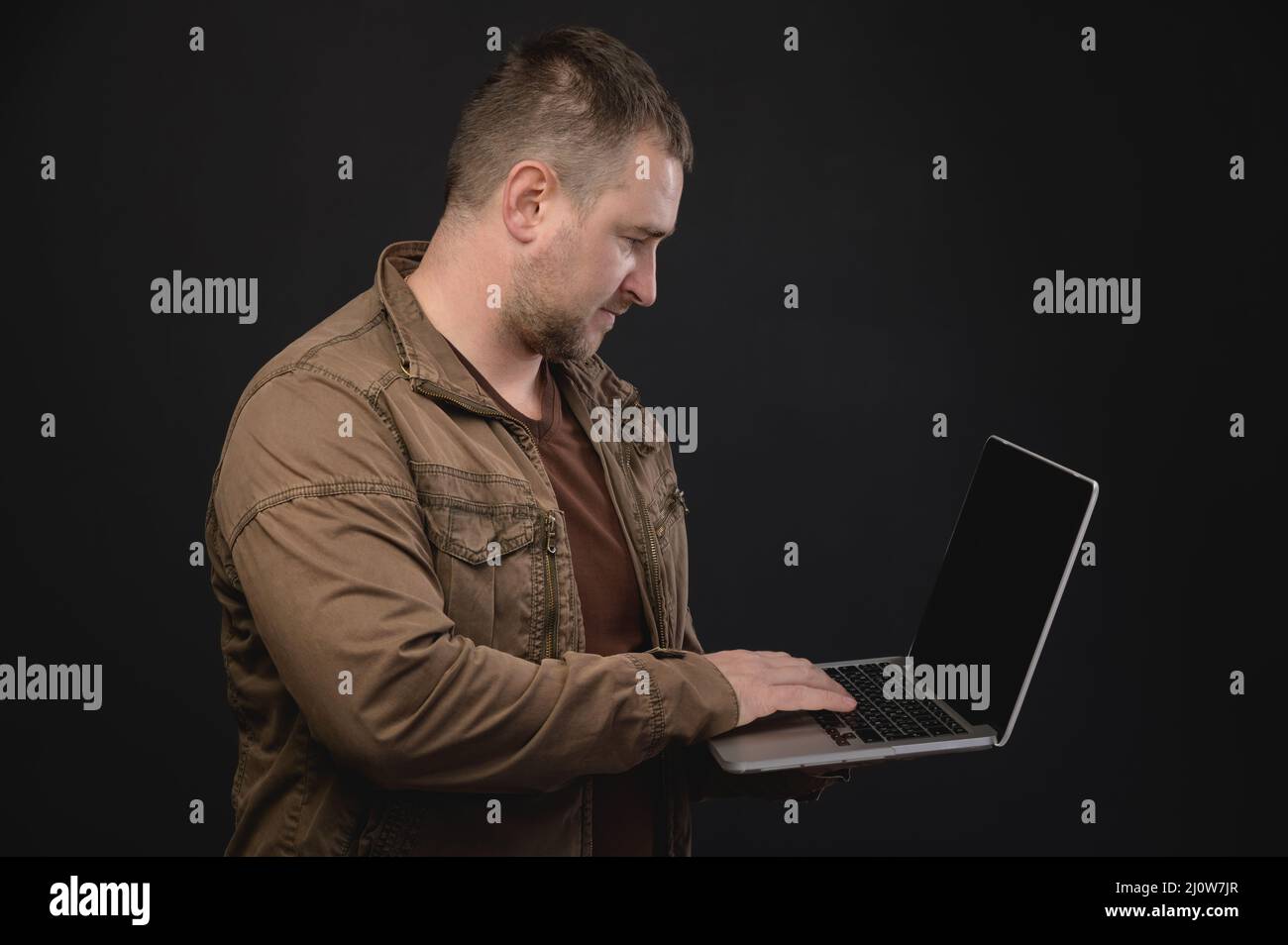 L'uomo caucasico di mezza età usa un computer portatile mentre si trova in studio. Ritratto di un freelance che naviga in Internet Foto Stock