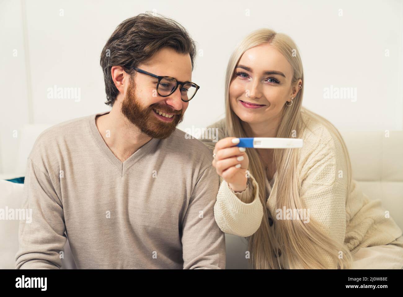 Eccitata giovane coppia caucasica donna mostrando un test di gravidanza positivo per la fotocamera ritratto . Foto di alta qualità Foto Stock
