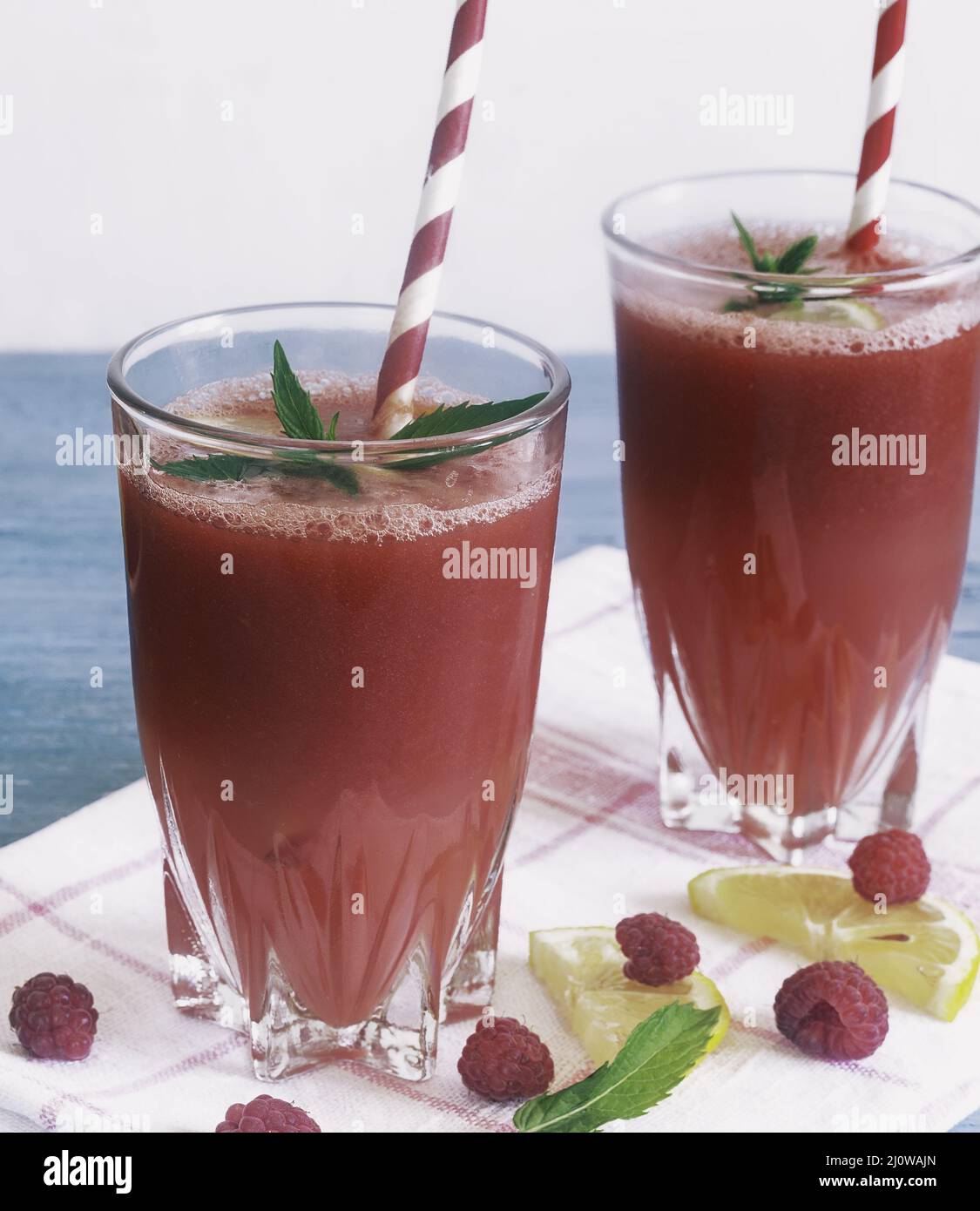 Succo di anguria in un bicchiere con limone e lamponi. Foto Stock