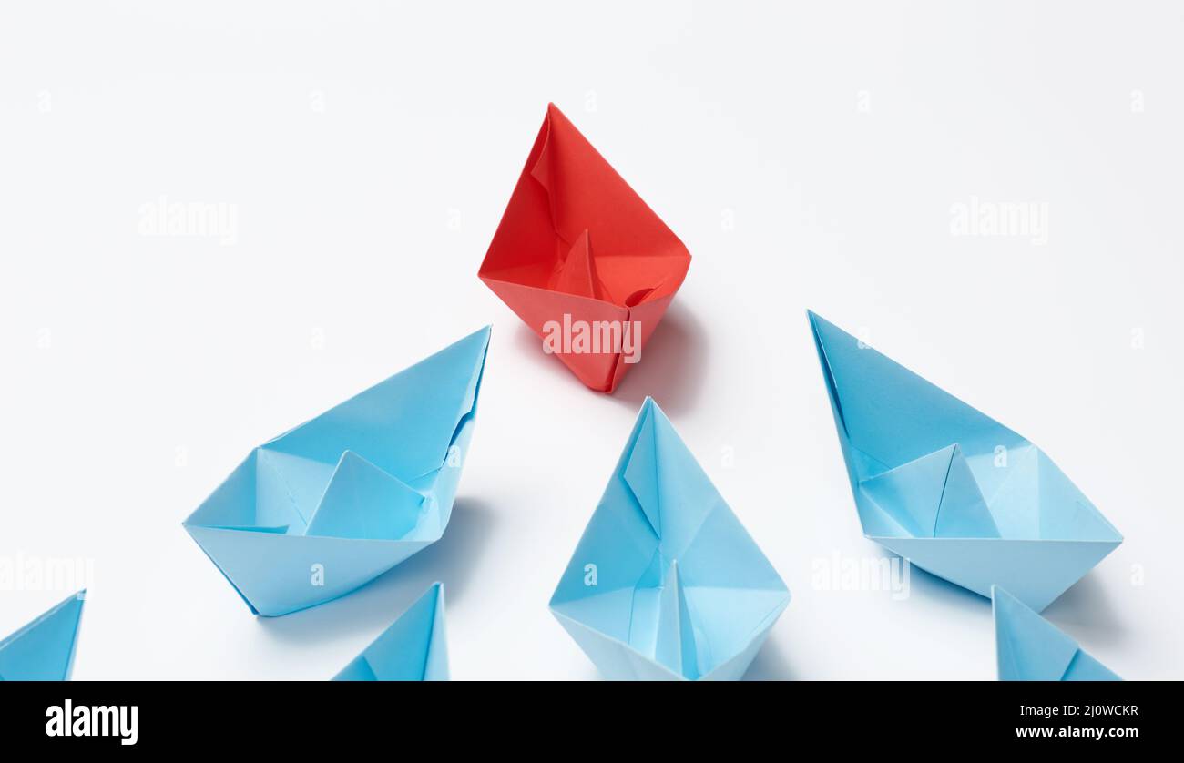 Gruppo di barche di carta su sfondo bianco. Concetto di un forte leader in una squadra, manipolazione delle masse, seguendo nuovi pers Foto Stock
