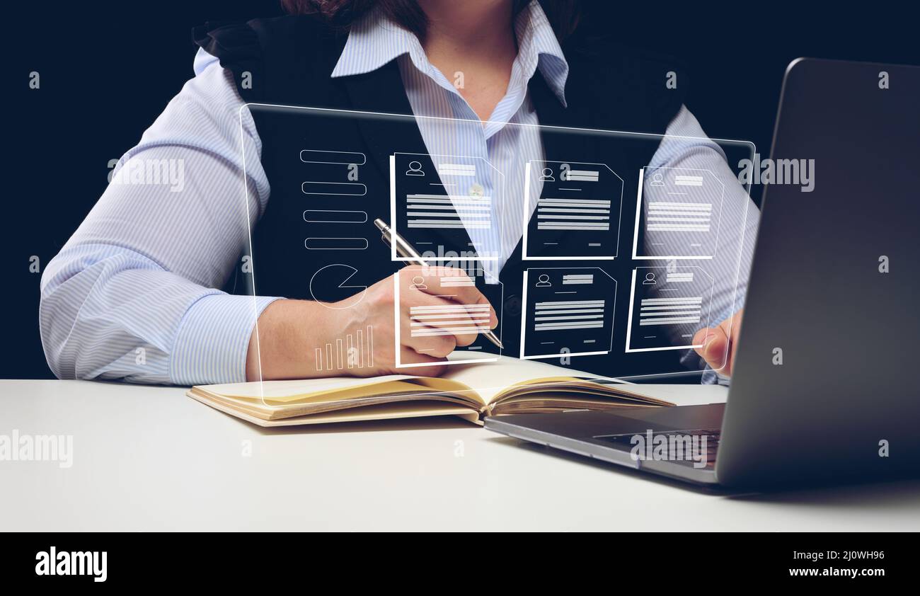 Una donna si siede a un tavolo e lavora a un portatile, il processo di reclutamento. Selezione di dipendenti di talento, sviluppo della carriera Foto Stock