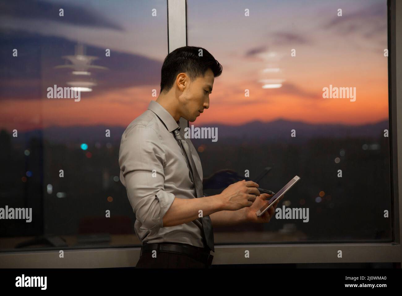 Un uomo d'affari cinese di successo che lavora con un tablet digitale in ufficio Foto Stock