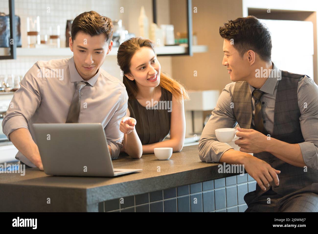 Colleghi di lavoro cinesi che lavorano con il computer portatile in caffetterie Foto Stock