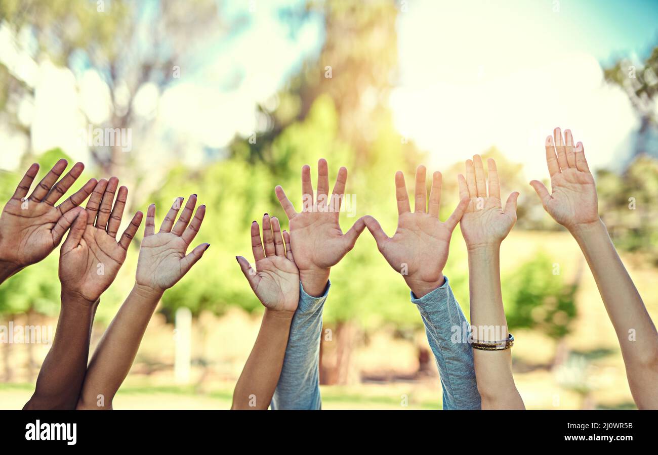 Scegliamo di stare insieme. Scatto corto di un gruppo vario di gente che alza le loro mani nell'aria. Foto Stock