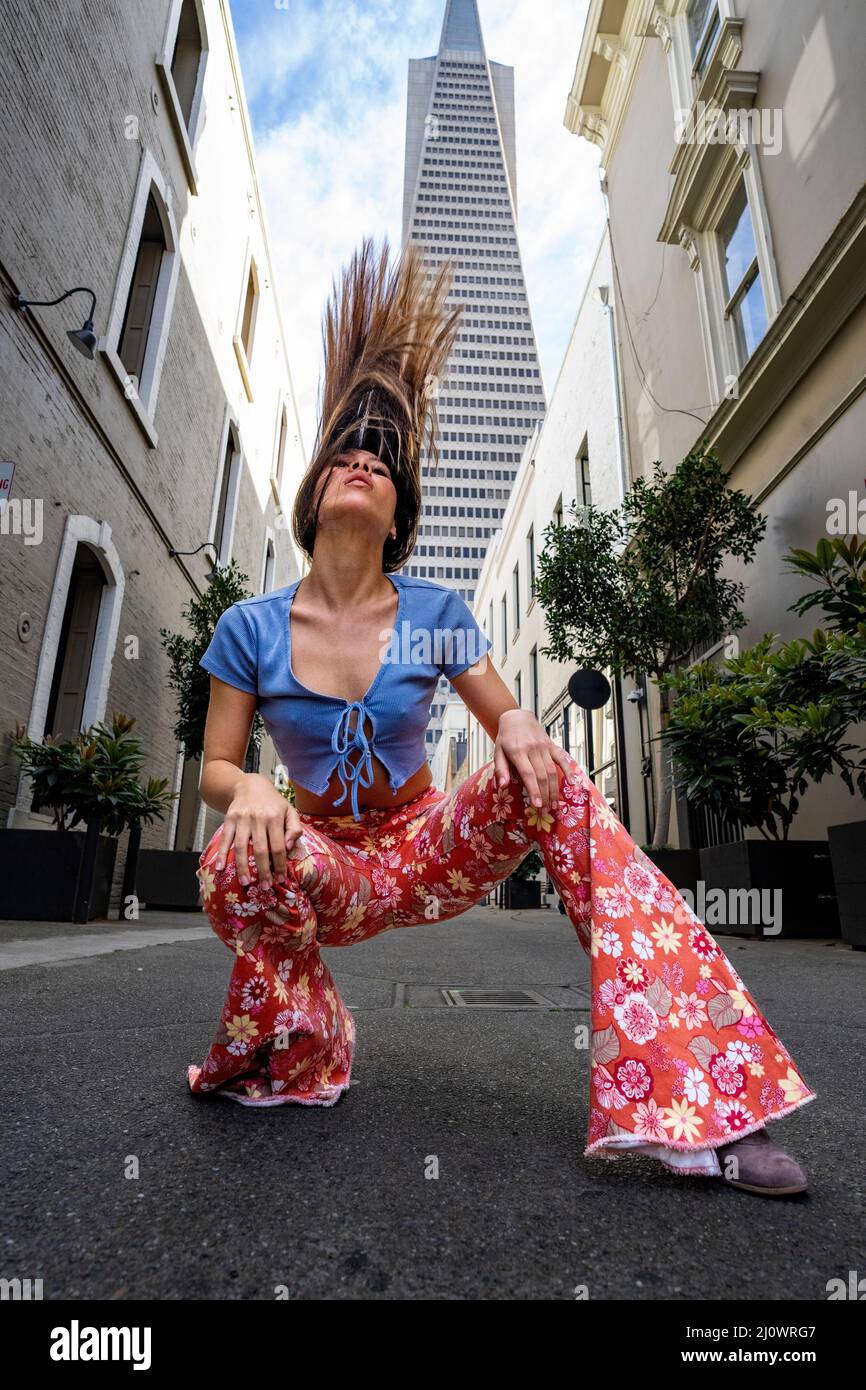 Adolescente donna che indossa abiti in stile 60s con l'iconica San Francisco Skyline in background Foto Stock