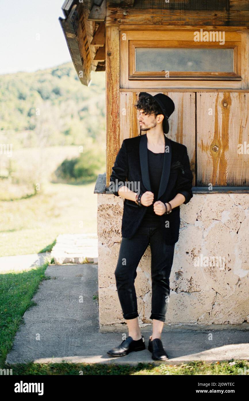 Il giovane uomo in un cappello si trova vicino al muro della casa Foto Stock