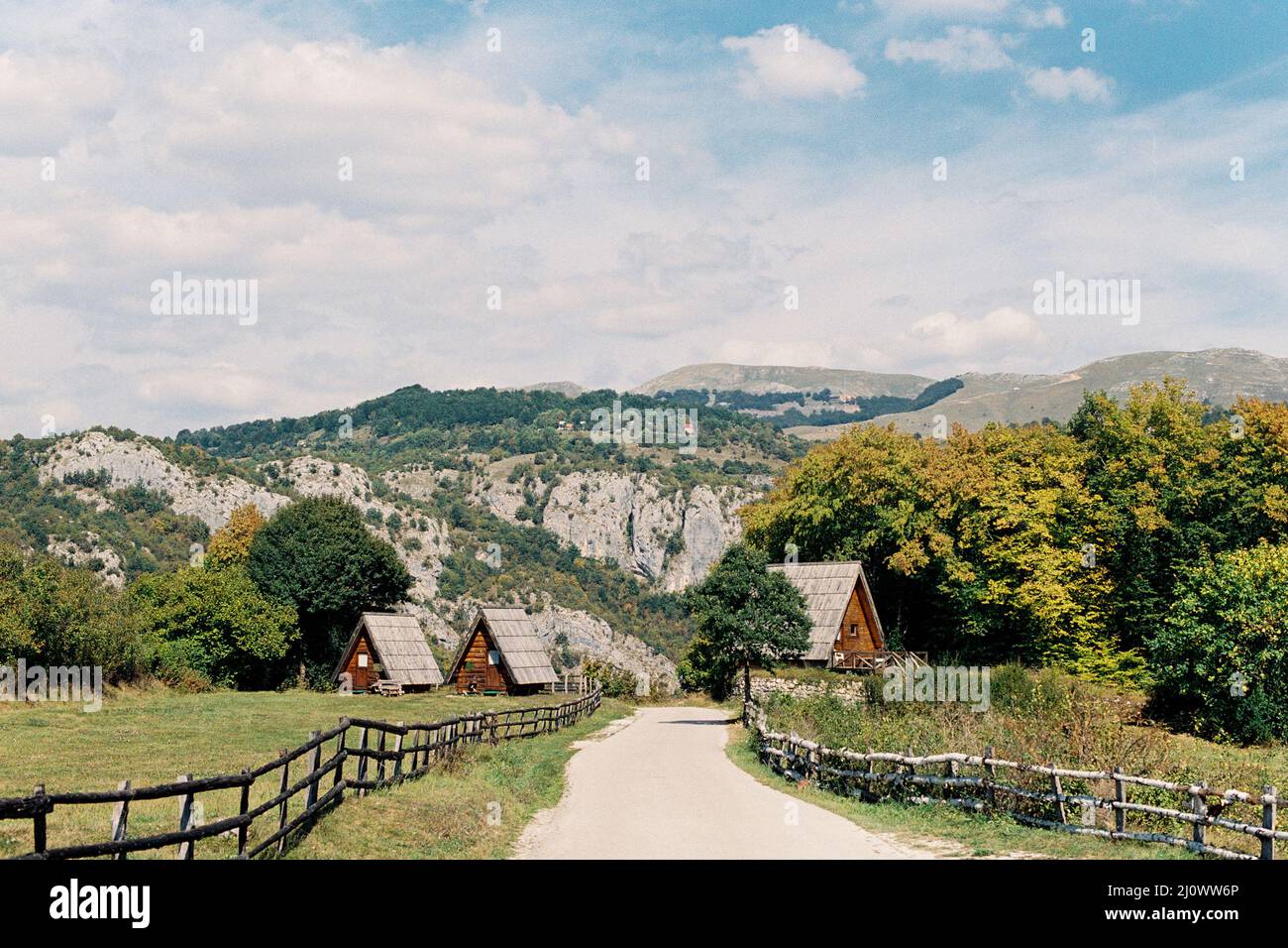 Strada che porta a case triangolari sullo sfondo di verdi montagne Foto Stock
