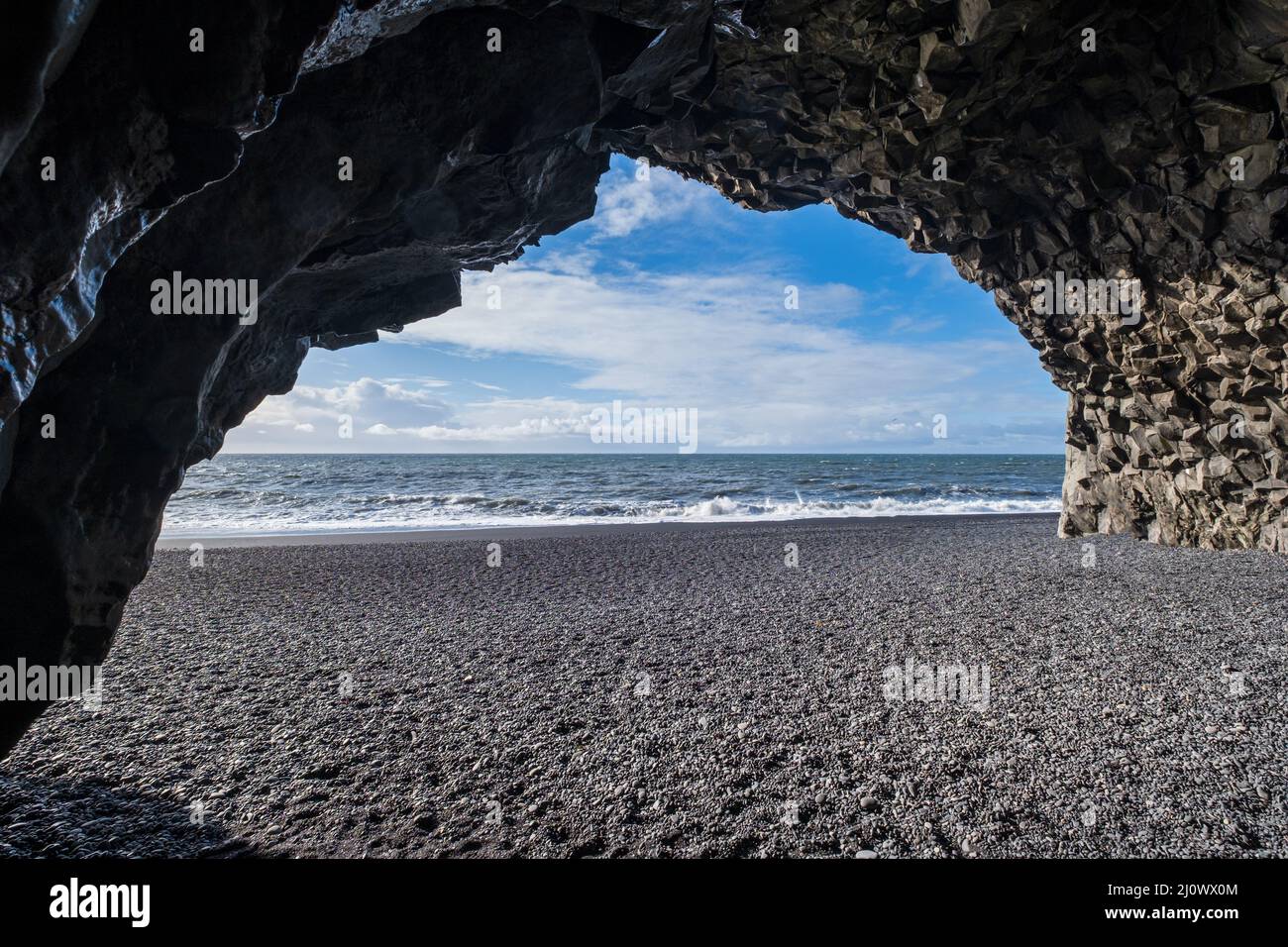 Vista sulla spiaggia di sabbia nera dell'oceano di Reynisfjara dalla grotta ai piedi del monte Reynisfjall. Colonne di roccia basaltica. Vik, Sout Foto Stock