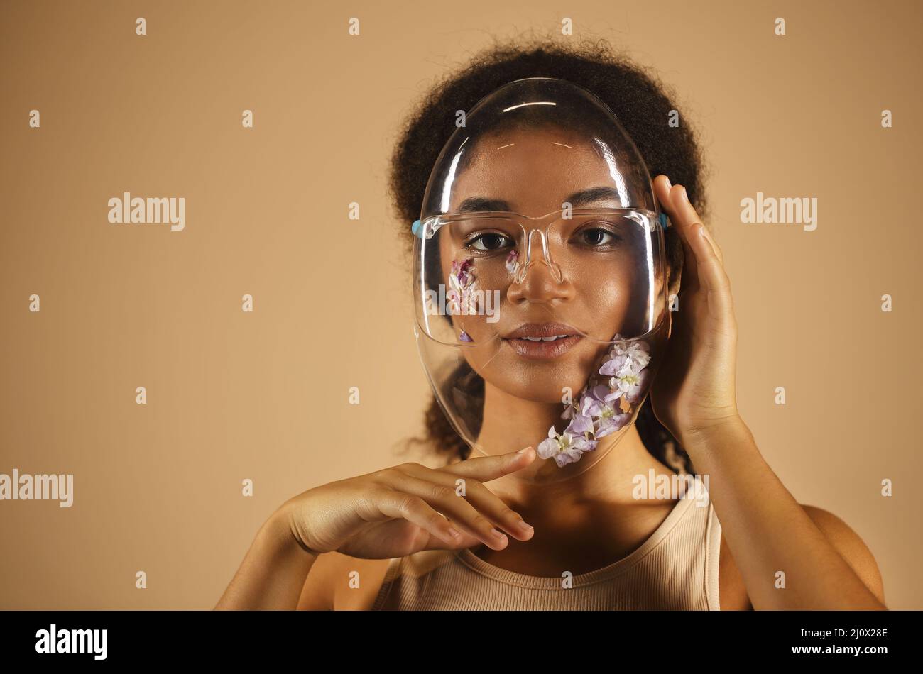 Allegra donna afroamericana in pieno viso protettivo trasparente scudo decorato con fiori Foto Stock