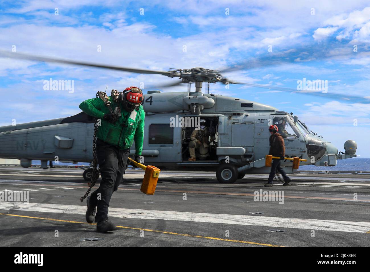 PHILIPPINE SEA (18 marzo 2022) Airman Christian Morgan, a sinistra, da Detroit, E Airman Domonick Storm, di Alburtis, Pa., entrambi assegnati ai “Raptors” di Helicopter Maritime Strike Squadron (HSM) 71, rimuovono cunei e catene da un elicottero MH-60R Sea Hawk sul ponte di volo del vettore aereo di classe Nimitz USS Abraham Lincoln (CVN 72). Abraham Lincoln Strike Group è in fase di implementazione pianificata nell'area delle operazioni della flotta USA 7th per migliorare l'interoperabilità attraverso alleanze e partnership, fungendo da forza di risposta pronta a supportare una regione indopacifica libera e aperta Foto Stock