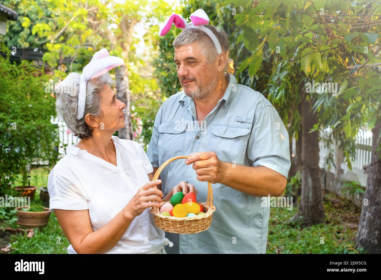 Coppia anziana felice con uova di pasqua in cestino all'aperto Foto Stock